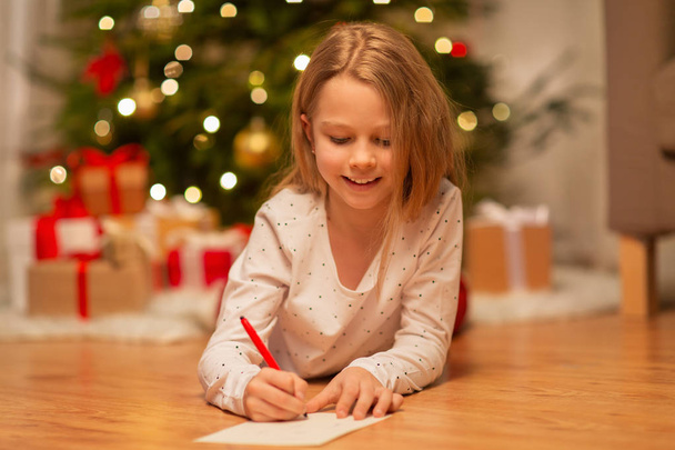 smiling girl writing christmas wish list at home - Foto, Bild