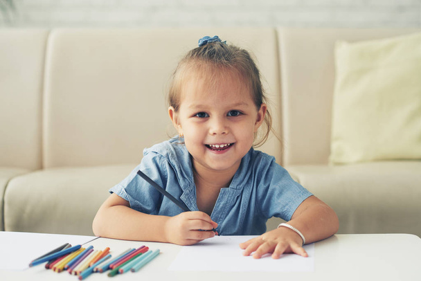 Porträt eines glücklichen Mischlingsmädchens, das mit Bleistiften zeichnet - Foto, Bild