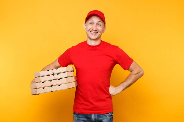 Repartidor en gorra roja, camiseta con cajas de pizza para pedidos de comida aisladas sobre fondo amarillo. Hombre empleado pizzaman o courier en uniforme sosteniendo pizza italiana en caja plana de cartón. Concepto de servicio
 - Foto, imagen