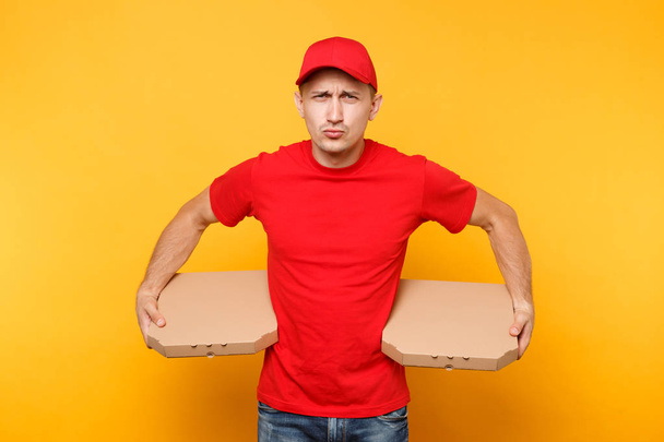 Liefermann mit roter Mütze, T-Shirt, das Pizzakartons bestellt, isoliert auf gelbem Hintergrund. männlicher Angestellter Pizzamann oder Kurier in Uniform mit italienischer Pizza in Pappschachtel. Dienstleistungskonzept - Foto, Bild