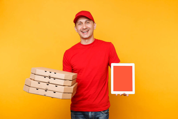 Entrega hombre en camiseta gorra roja dando pizza pedido de comida en cajas de caja plana sobre fondo amarillo. Empleado pizzaman mensajero mantenga la computadora PC tableta con la pantalla vacía en blanco maqueta. Concepto de servicio
 - Foto, Imagen