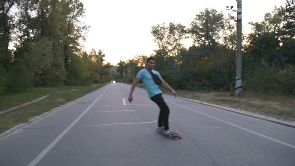 Carrera mixta hipster hombre longboarder carreras en el parque público de la ciudad en cámara lenta
 - Imágenes, Vídeo