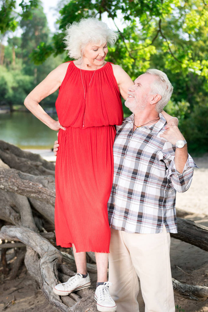 Happy senior woman standing on the log and looking at her husband - Photo, image