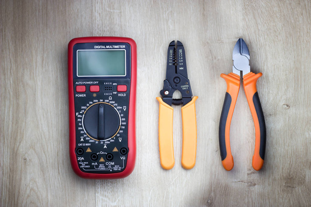 Different electrical tools on wooden table. Digital multimeter, cutting pliers and cable stripper. Top view. - Zdjęcie, obraz