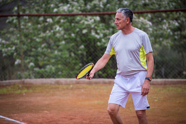 Kypsä mies pelaa tennistä
 - Valokuva, kuva