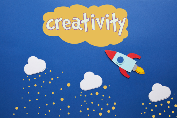 white clouds and rocket on blue background with "creativity" lettering - Фото, изображение