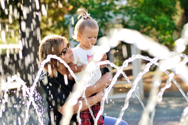mother and daughter playing with fountain - Foto, imagen