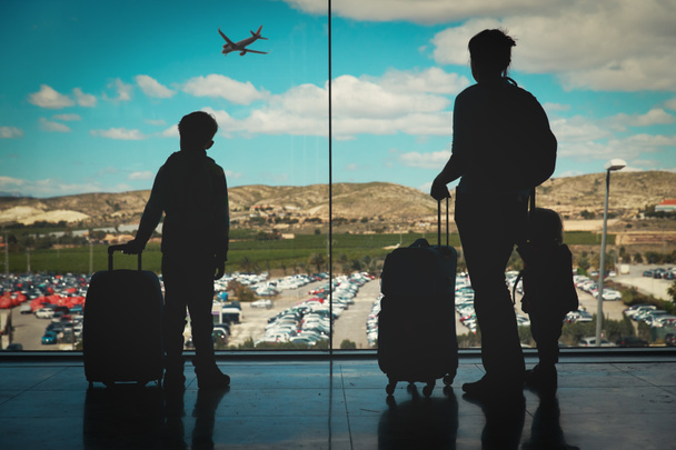 madre con niños y equipaje mirando aviones en el aeropuerto
 - Foto, Imagen