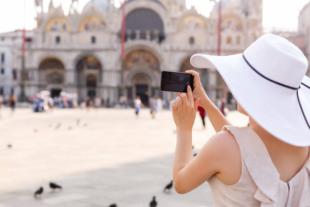 schöne junge Frau beim Fotografieren in Venedig, Italien auf der Piazza San Marco - Foto, Bild