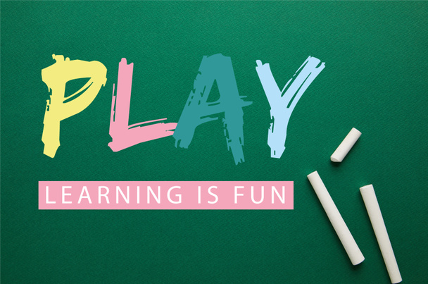 top view of white chalks on green blackboard with "play - lettering is fun" lettering - Φωτογραφία, εικόνα