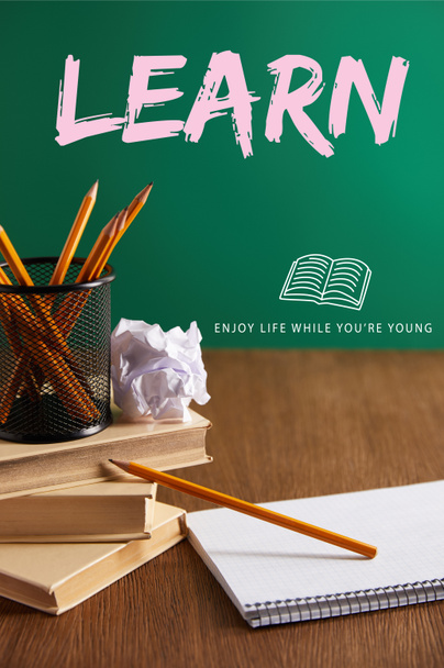 libros, copybook, papel arrugado y lápices en la mesa de madera con letras de "aprender - disfrutar de la vida mientras eres joven"
 - Foto, Imagen