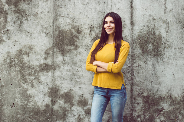 Pewny siebie piękno. Piękna młoda kobieta, patrząc na kamery z uśmiechem stojąc na zewnątrz w tle betonowych  - Zdjęcie, obraz