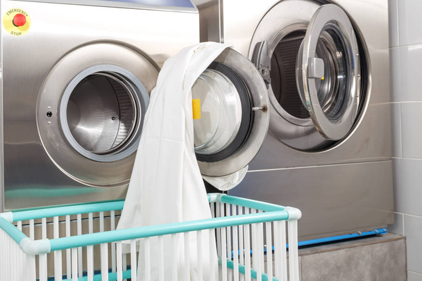 Machine à laver surchargée de vêtements et panier vide dans la buanderie
 - Photo, image