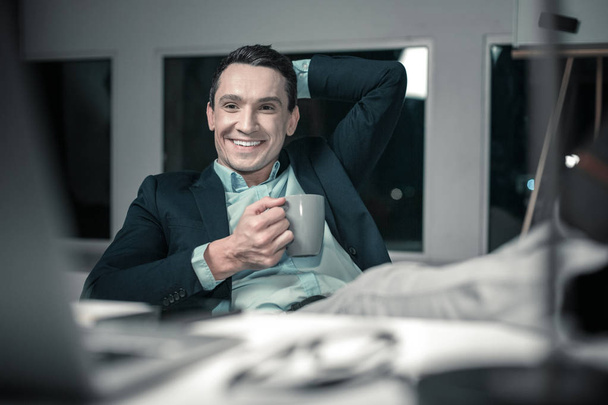Smiling nice man holding a cup of coffee - Zdjęcie, obraz