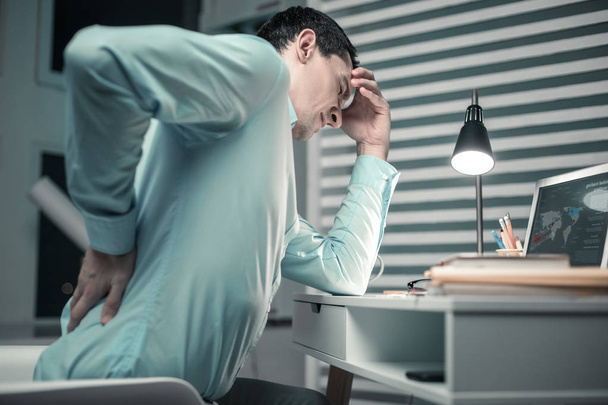 Trabajador de oficina inteligente sintiendo dolor de espalda después de sentarse todo el día
 - Foto, Imagen
