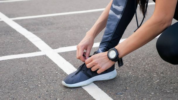 Nahaufnahme einer Läuferin, die ihre Schuhe schnürt - Foto, Bild