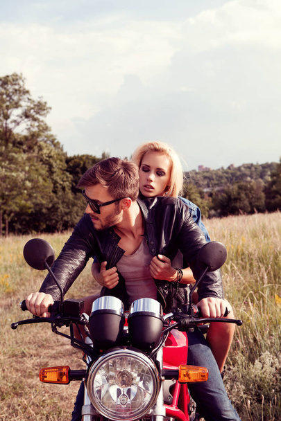 young sensual couple posing on bike outdoors - Фото, изображение