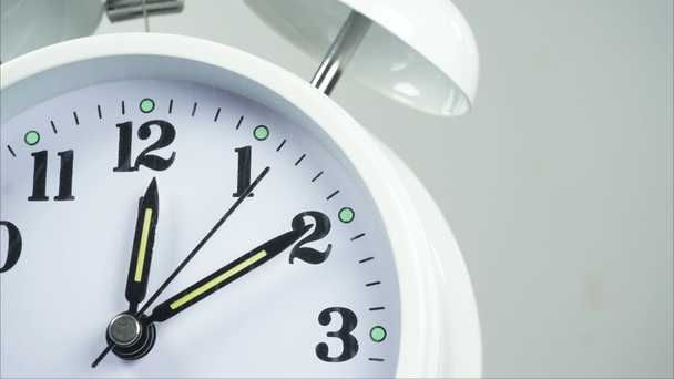 Cierre del reloj de alarma blanca frente al inicio del tiempo 11.57 am o pm. sobre fondo blanco, El tiempo se desplaza rápidamente, concepto de tiempo. - Metraje, vídeo