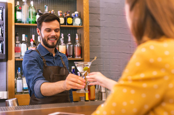 Happy barman smiling to the visitor while giving her alcohol - Photo, image