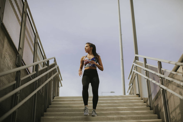 Nuori nainen juoksee yksin alas portaita ulkona
 - Valokuva, kuva