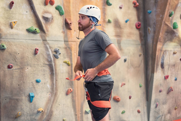 Uomo arrampicatore che si prepara a scalare la parete artificiale di arrampicata indoor
 - Foto, immagini