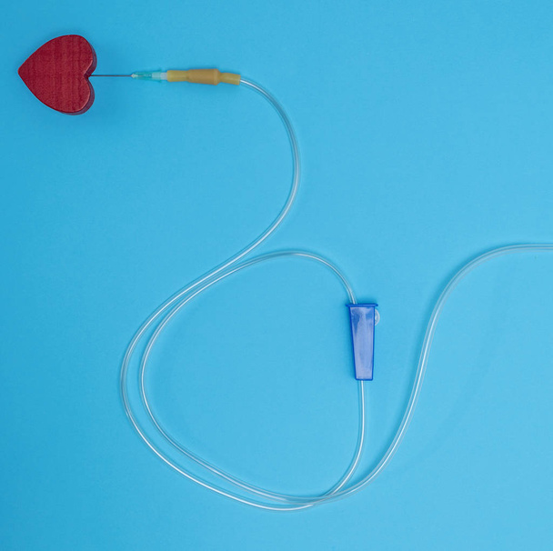 empty plastic dropper with needles and red heart on blue background, medical device - Photo, Image