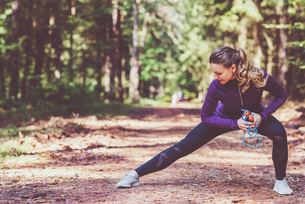 Young pretty woman jogging and making exercises in the sunny forest - Foto, imagen