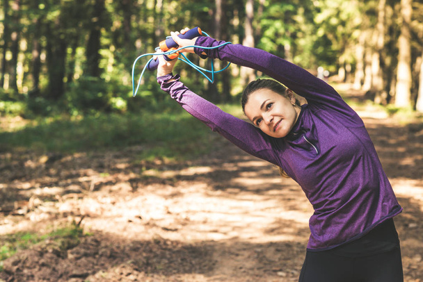 Young pretty woman jogging and making exercises in the sunny forest - Foto, Bild