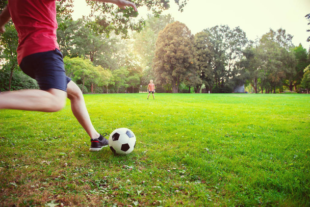 Happy young father play with his little son football in green sunny park - Foto, imagen