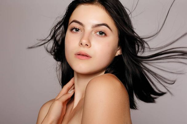 Beautiful woman with perfect skin and bare shoulders on a gray background - Fotó, kép