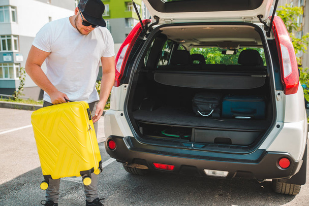 man putting bags in car trunk. ready for car travel. sunny morning - Foto, Bild