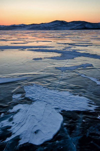 Uitzicht op prachtige tekeningen op ijs van scheuren en diepe gasbellen op oppervlak van Baikal lake in de winter met de berg, Rusland - Foto, afbeelding