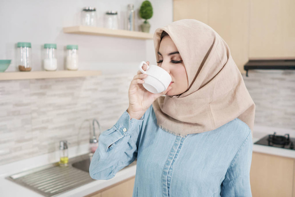 beautiful young woman wearing hijab drinking a cup of coffee - Valokuva, kuva