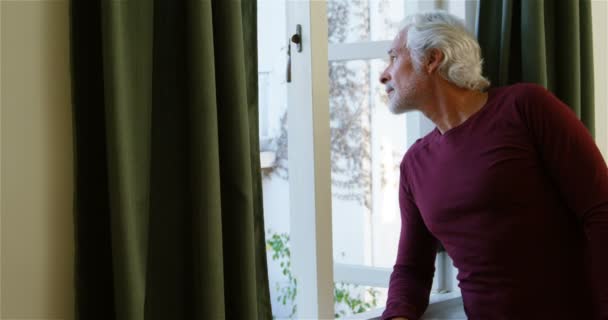 Senior man looking through window in bedroom at home 4k - Video, Çekim