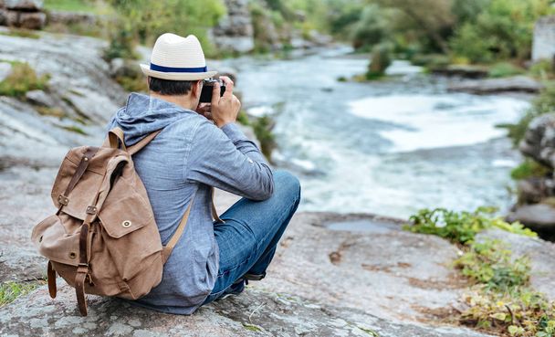 Man making pictures with a camera while traveling. Natural canyon with view of the mountain river. Concept of travel. - Foto, Imagem