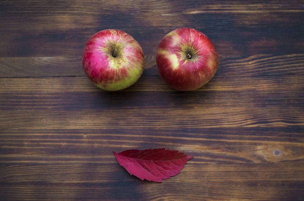 Two red apples and autumn leaf on the wooden background. - Fotó, kép