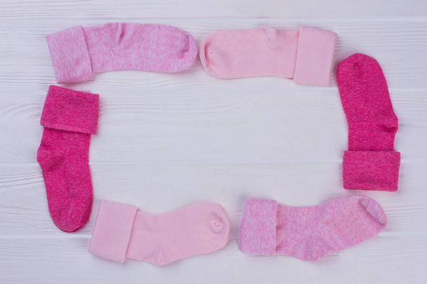 Roze baby sokken netjes rondslingeren. Witte houten bureau achtergrond. - Foto, afbeelding
