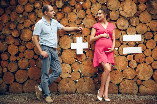 Pareja enamorada acurrucada embarazada, esperando al bebé sobre fondo de madera. ejemplo matemático
 - Foto, imagen