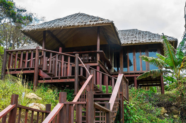 Bungalow de madeira com escadas e telhado de palha
 - Foto, Imagem