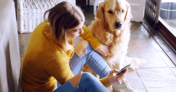 Women using mobile phone with her dog at home 4k - Filmagem, Vídeo