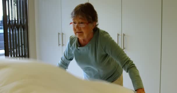 Senior woman making bed in bedroom at home 4k - Imágenes, Vídeo