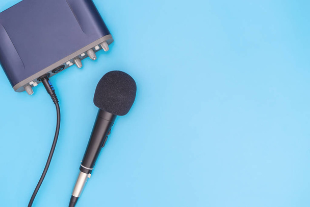 Black microphone on blue background for music concept - Photo, image