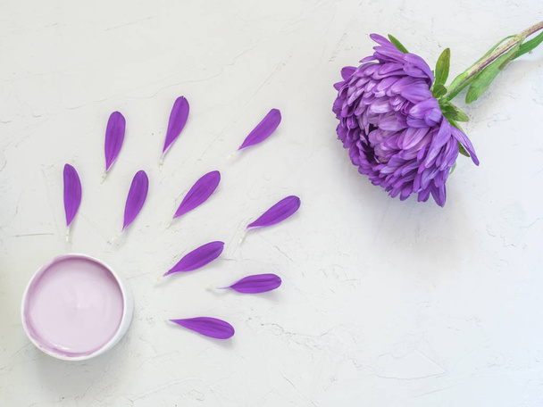 Purple cosmetic cream and purple flower petals on white background. Creative beauty fashion cosmetics photo. Flat lay - Foto, Bild