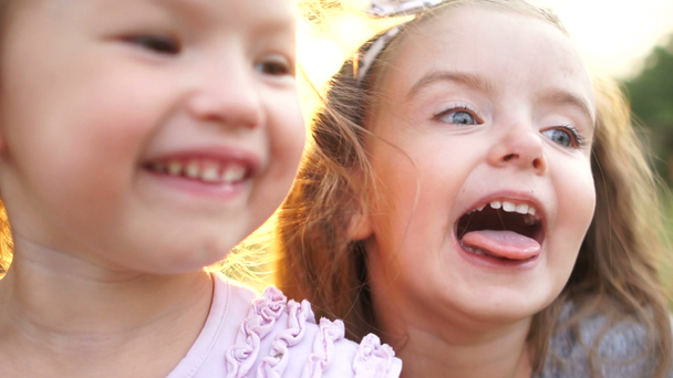 Bebekler, iki küçük kız kardeş oynaşman, dilini göster ve yüzleri olun. Çocuk yürümek hayat, Bahçe, aktif şekilde mutlu tatiller - Video, Çekim