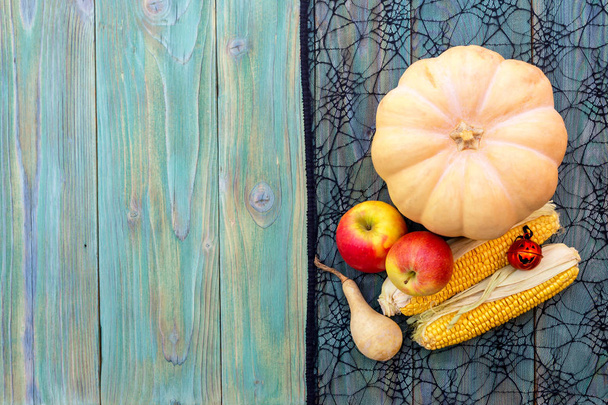Концепция Хэллоуина. Натюрморт с тыквой, яблоками и кукурузой на деревянном фоне крупным планом
. - Фото, изображение