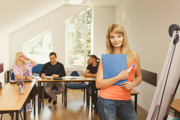 Education, high school, teamwork and people concept - smiling student girl with notebook standing in front of students her group mates in classroom - Φωτογραφία, εικόνα