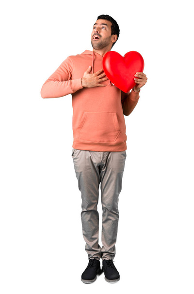 Повне тіло людини в рожевому светрі, що тримає велику ікону серця на ізольованому білому тлі
 - Фото, зображення