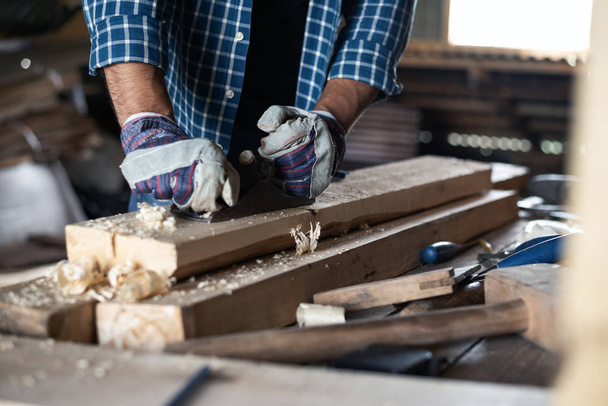 Los hombres de cerca manos en guantes con cepilladora maneja tablero de madera, trabajo manual, bricolaje, flujo de trabajo
 - Foto, Imagen