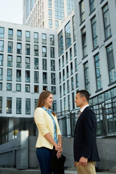 beautiful guy and girl in suits, discussing business on the background of a building in the summer - Foto, Bild
