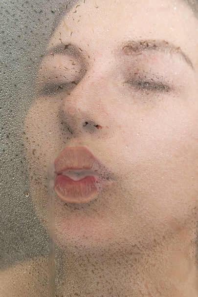 Woman kisses glass in the shower - Foto, afbeelding